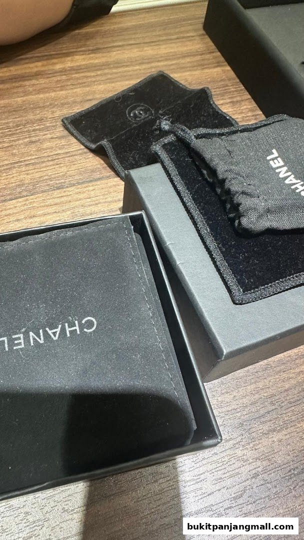 Chanel branded packaging and pouches are displayed on a wooden surface.