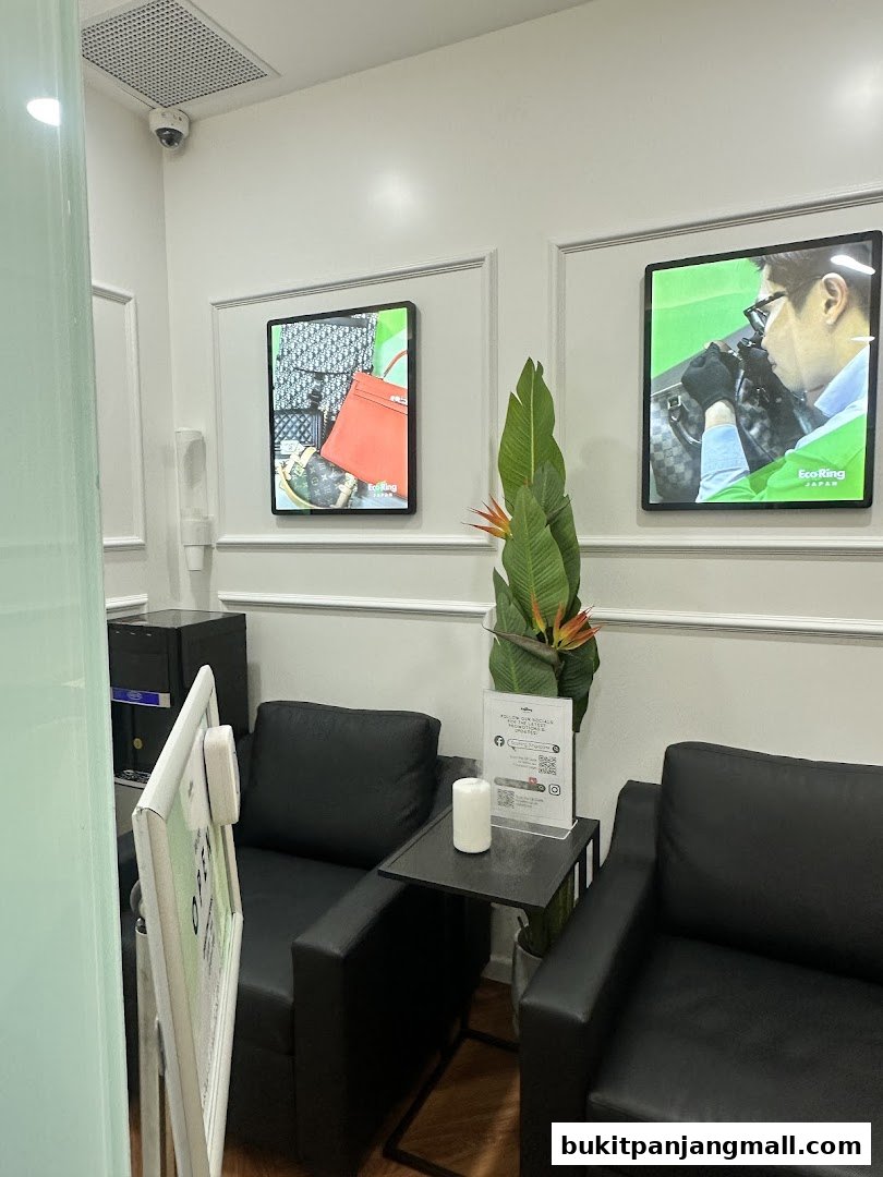 Interior waiting area with black leather chairs, artwork, and a plant.