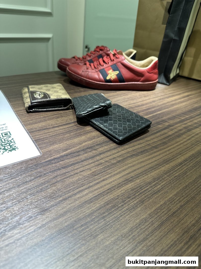 Red designer sneakers and wallets displayed on a wooden table.