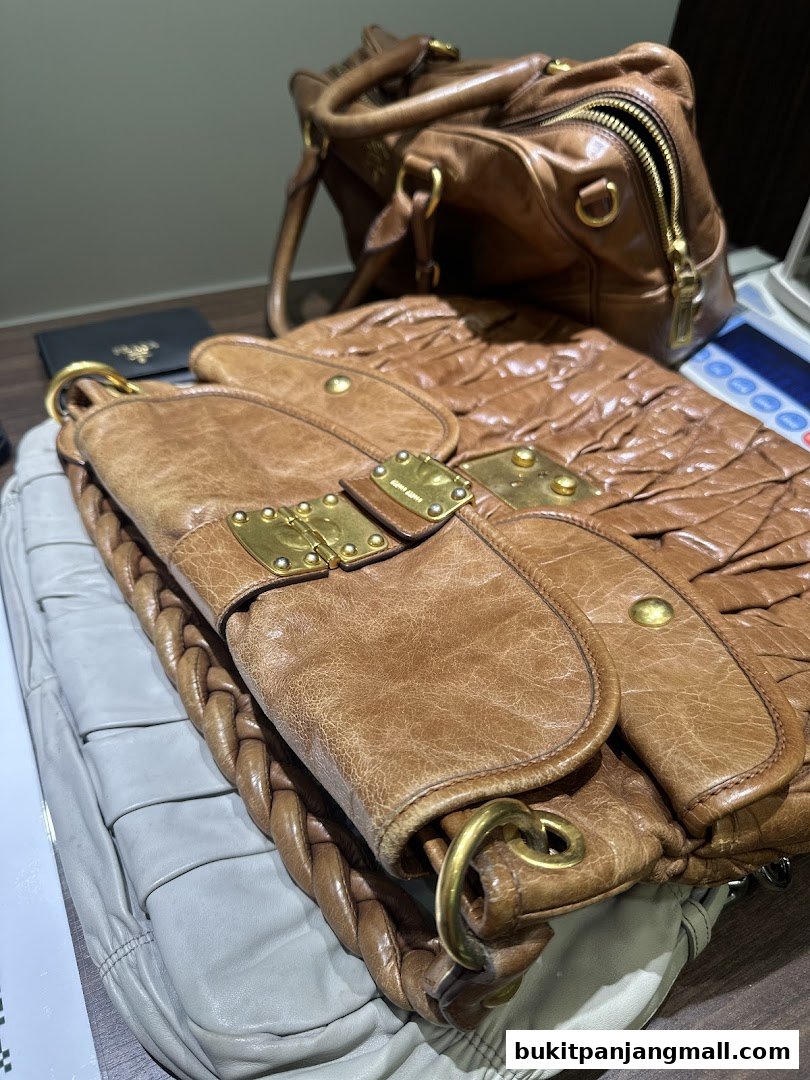 Close-up of brown leather designer bags with gold hardware and braided details.