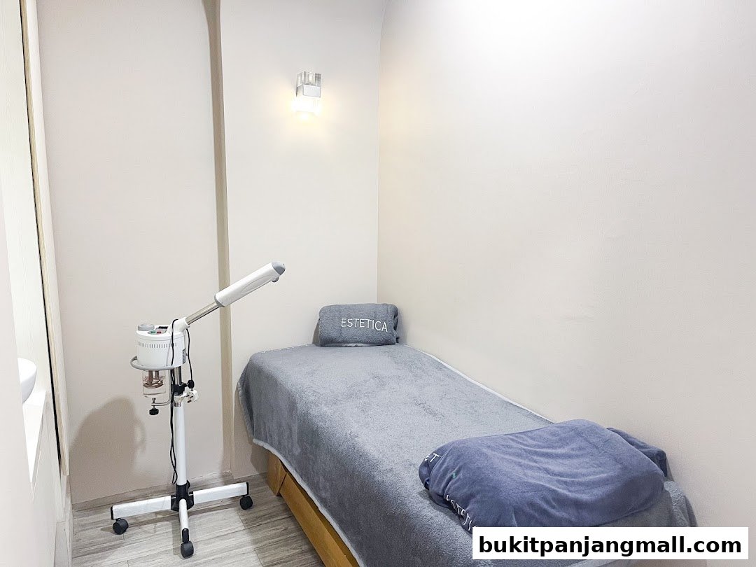 A clean and serene treatment room at Estetica Beauty, featuring a massage bed and facial steamer.
