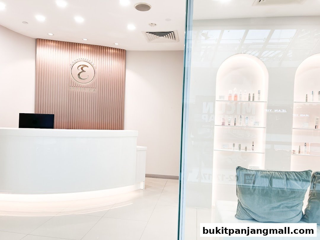 The reception area of Estetica Beauty, featuring a modern white counter and a rose gold accent wall with the shop's logo.