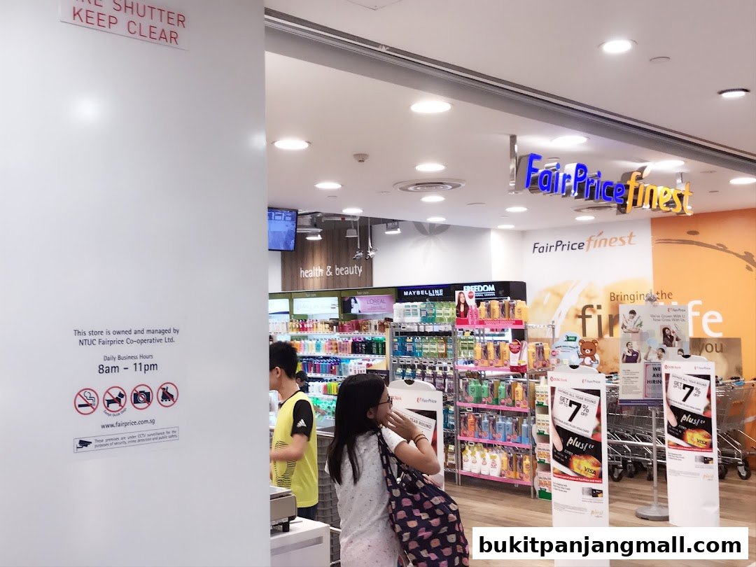 The entrance of a FairPrice Finest store, showcasing health and beauty products and promotional displays.