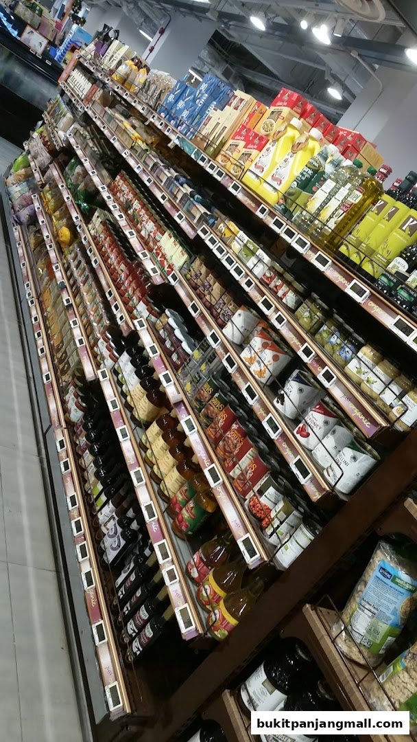 A wide aisle of a supermarket with shelves stocked with various food and beverage products.