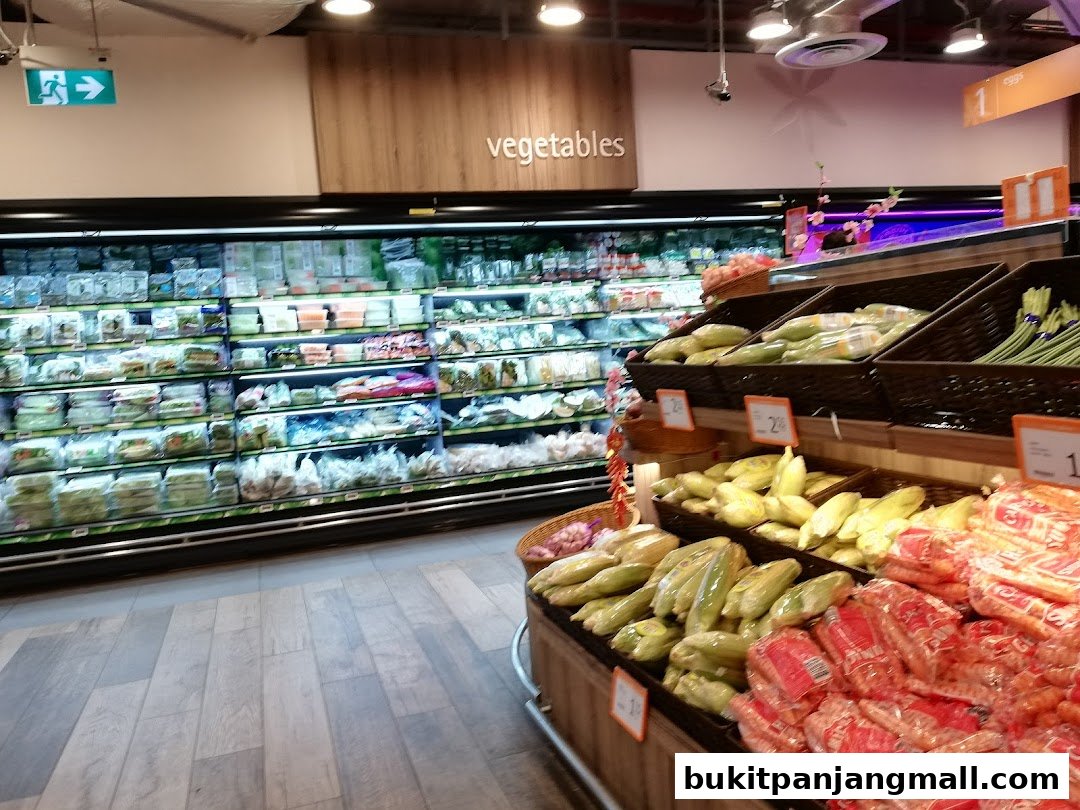 A well-stocked grocery store aisle featuring fresh vegetables and produce in refrigerated displays and baskets.