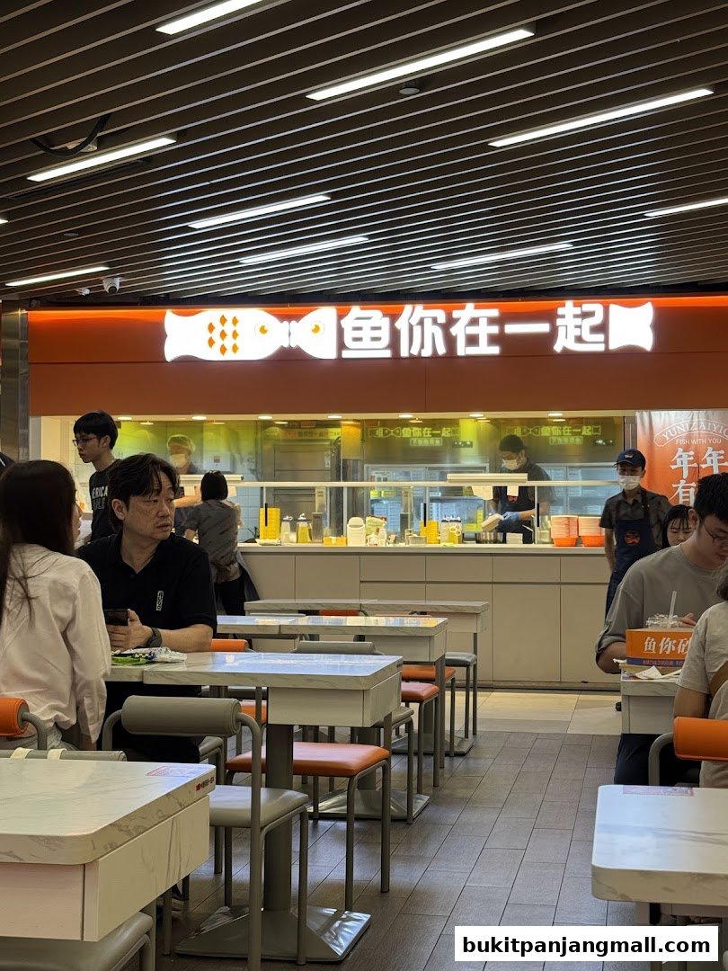 Interior of a brightly lit restaurant with tables and chairs, showing the shop's sign and staff.