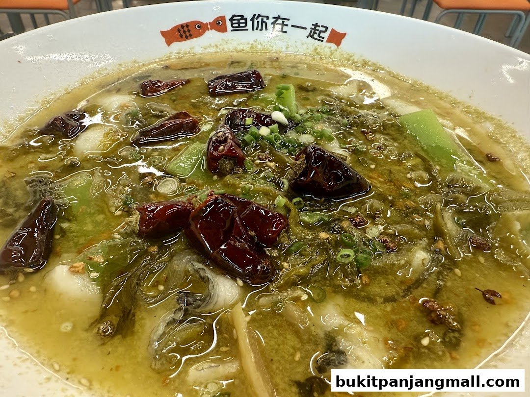 A close-up of a bowl of fish soup with chili peppers and vegetables.