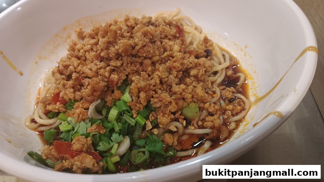 A close-up of a bowl of noodles topped with minced meat and green onions.