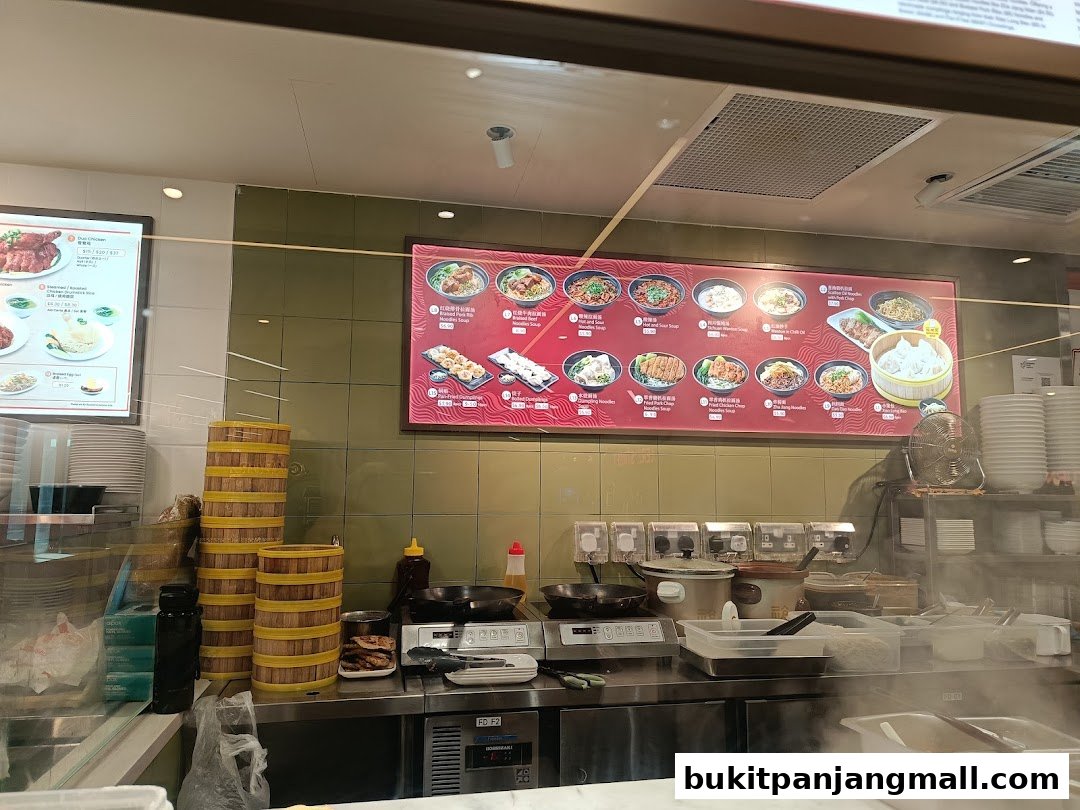 A food counter with a menu board displaying various dishes and steaming food preparation.