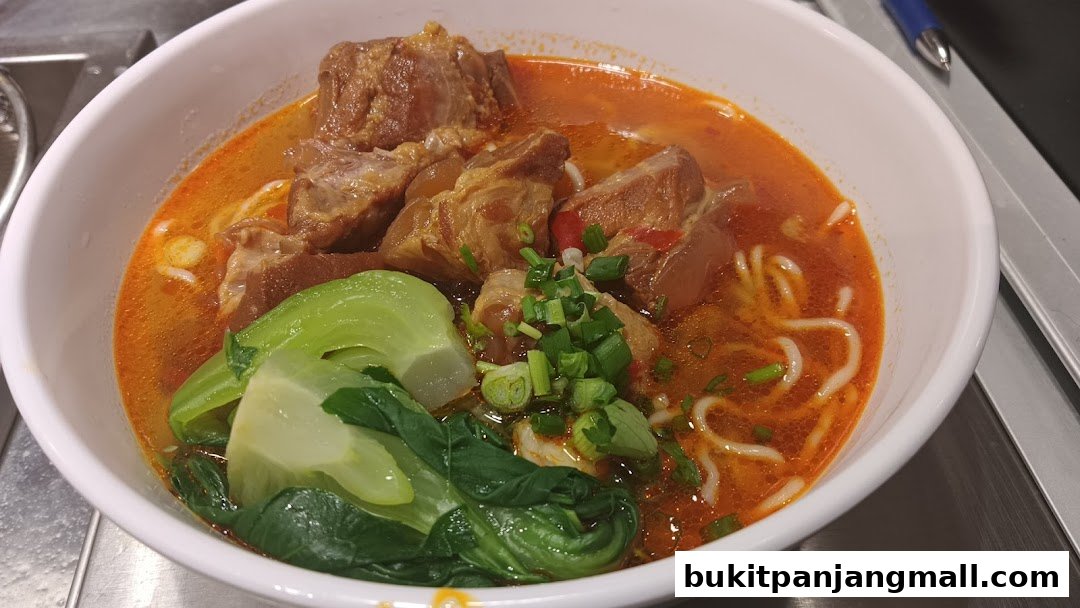A close-up of a steaming bowl of noodle soup with tender meat and fresh greens.