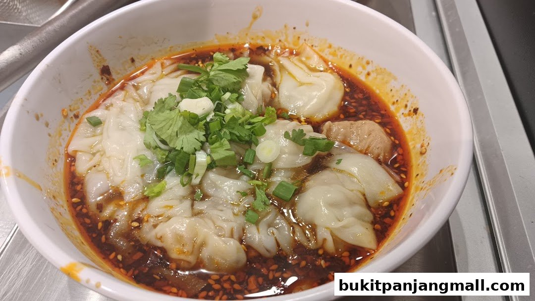 A bowl of wontons in spicy chili oil, garnished with cilantro and scallions.