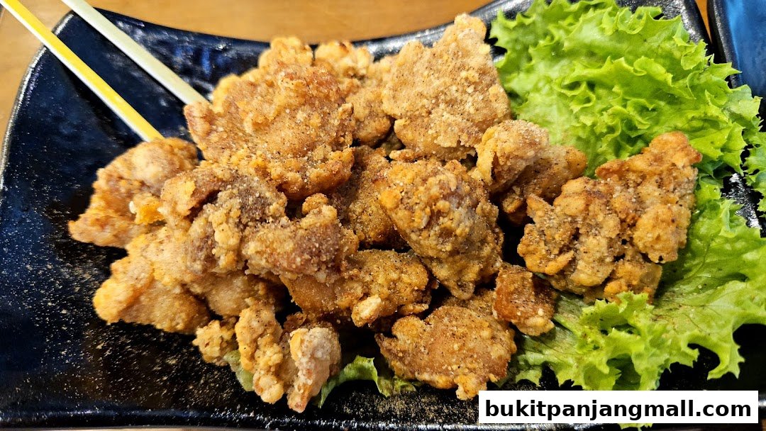 A close-up shot of crispy fried chicken pieces served on a black plate with lettuce.