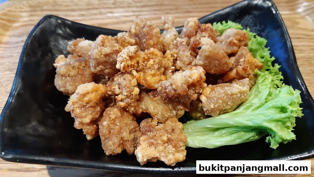 A black plate filled with crispy fried chicken pieces and a side of fresh lettuce.