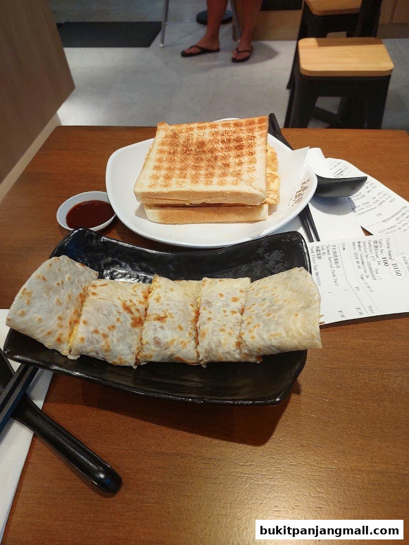 A table with a plate of sliced savory crepes and a plate of toasted bread with dipping sauce.