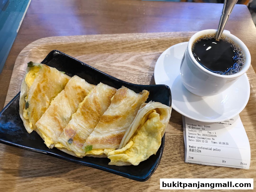 A plate of sliced egg crepes served with a cup of black coffee on a wooden tray.
