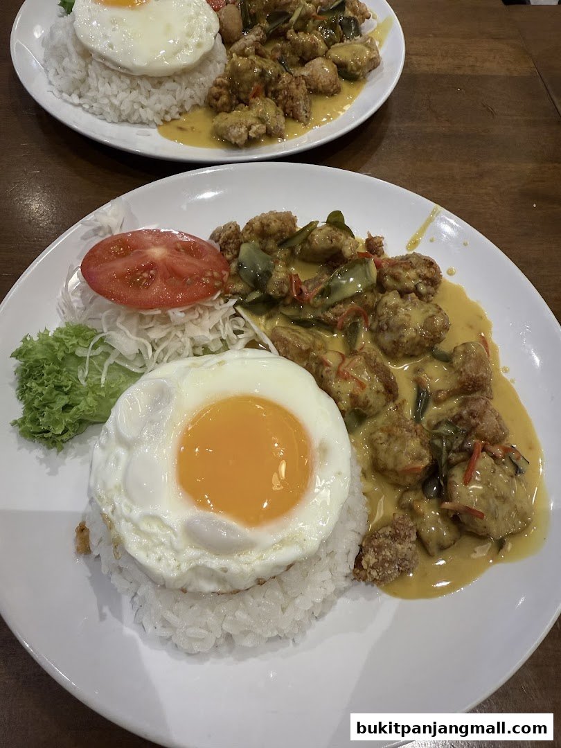 Two plates of rice topped with fried chicken, a sunny-side-up egg, and curry sauce.
