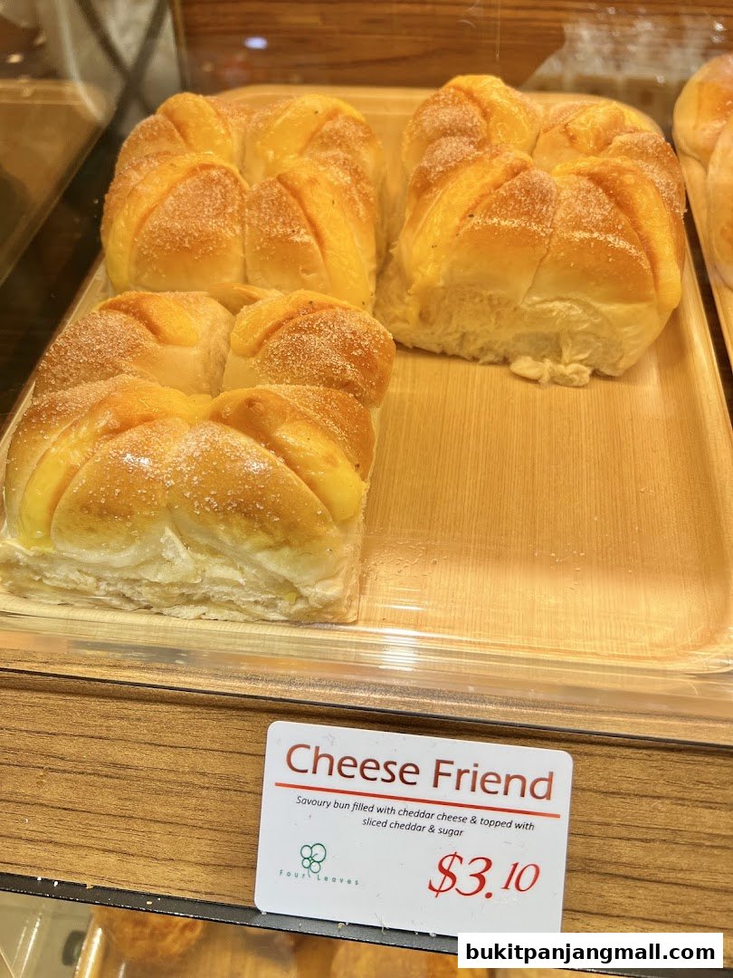 A close-up of a savory bun filled with cheddar cheese, topped with sugar.