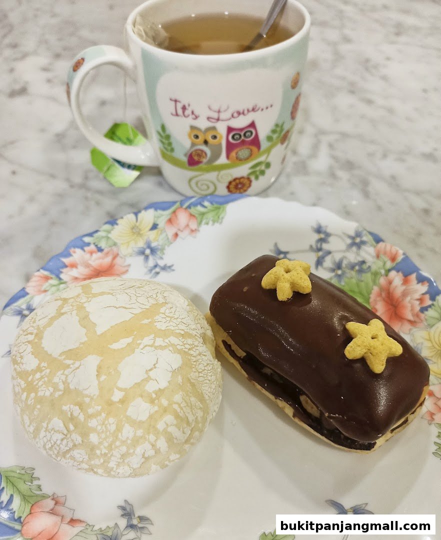 A delightful assortment of baked goods, including a chocolate-glazed pastry and a powdered cookie, served with a cup of tea.