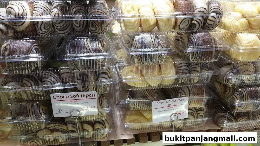 A display of freshly baked bread rolls with chocolate and custard fillings in clear plastic packaging.