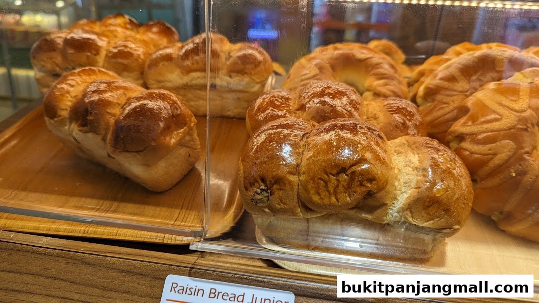 A close-up of freshly baked raisin bread loaves displayed in a bakery case.