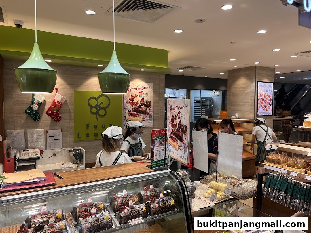 A bakery counter with Christmas log cakes and pastries, staffed by employees.