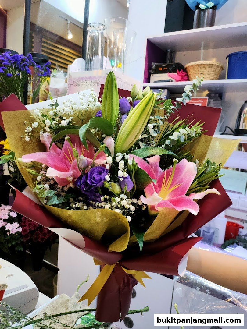 A beautifully arranged bouquet of pink lilies, purple lisianthus, and baby's breath.
