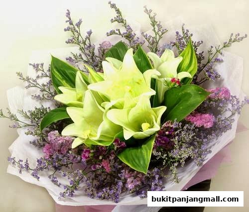 A beautiful bouquet of white lilies and purple statice flowers, elegantly wrapped.