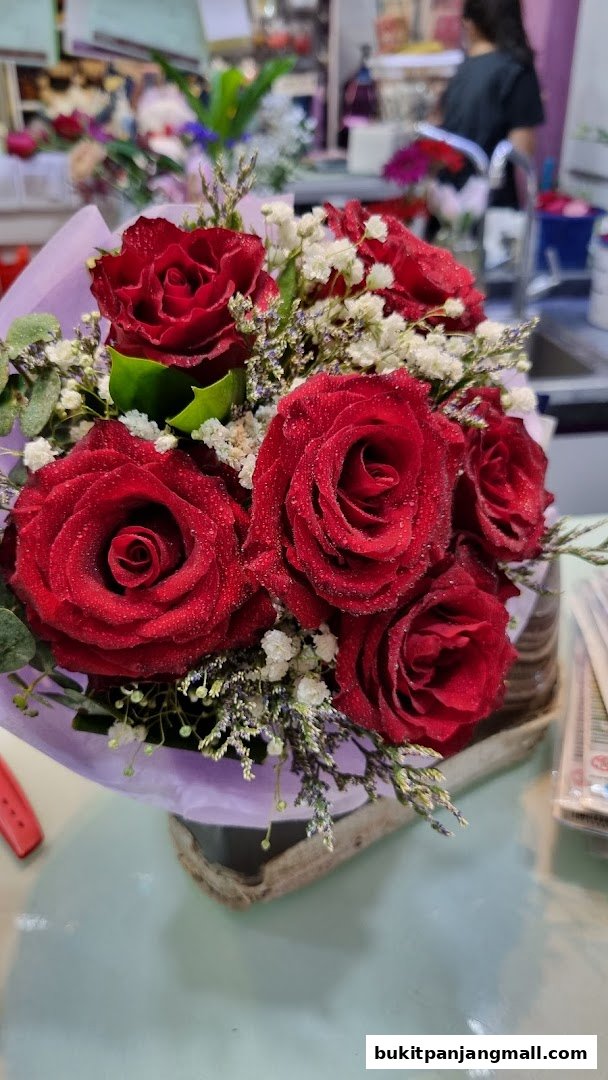 A close-up of a bouquet of vibrant red roses with delicate white filler flowers.