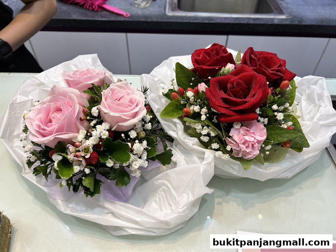 Two small floral arrangements, one with pink roses and the other with red roses, are displayed on a table.