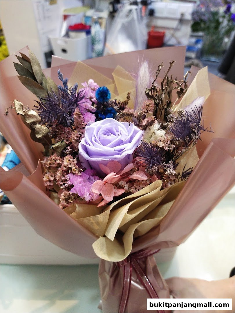 A beautifully arranged bouquet of preserved flowers in shades of purple and pink.
