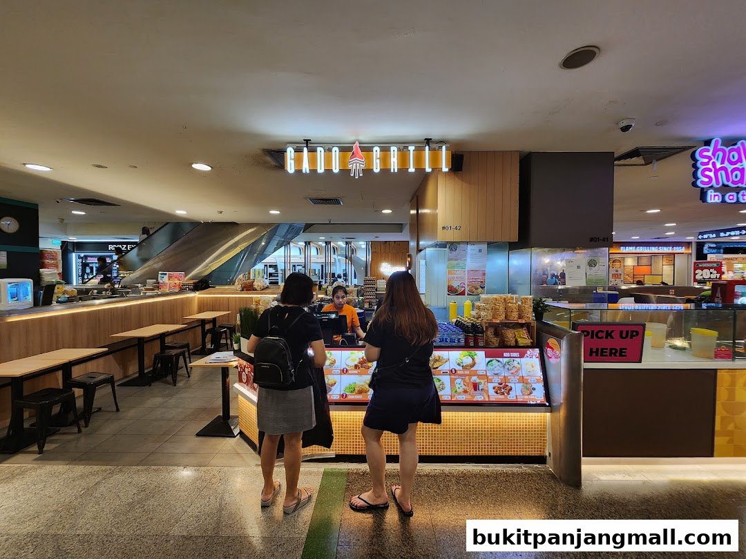 Customers at the Gado Grill counter with a display of food items and seating area.