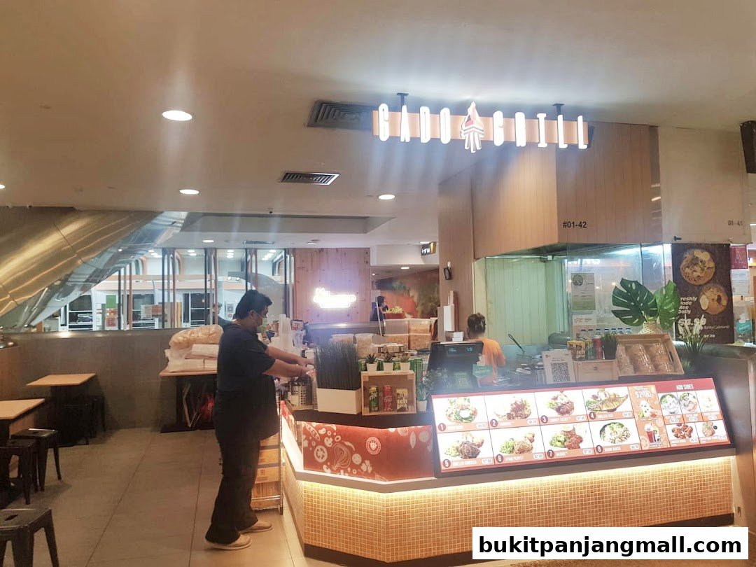 A Gado Grill restaurant counter with staff and a display of food items.