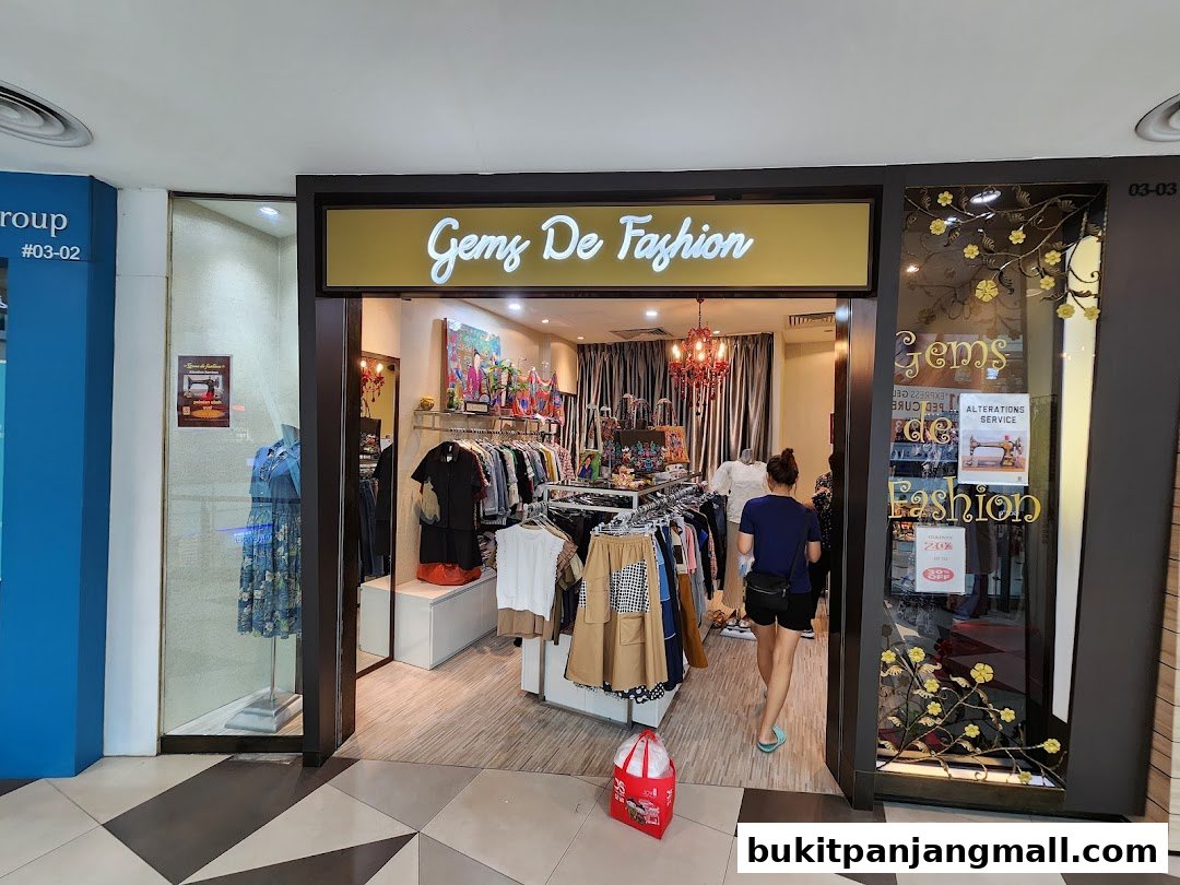 The entrance to Gems de Fashion, a clothing store with racks of apparel and a mannequin.