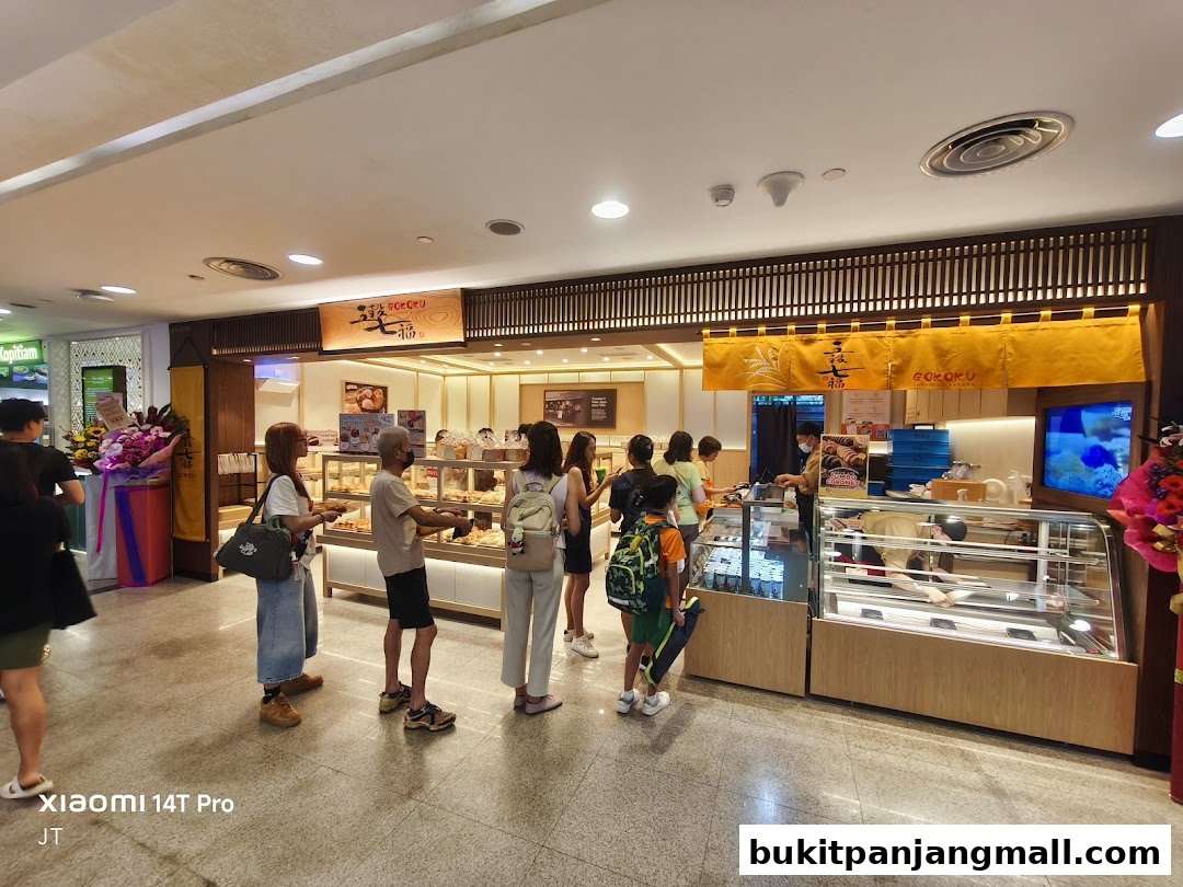 Customers queue at Gokoku Japanese Bakery, with displays of baked goods visible.