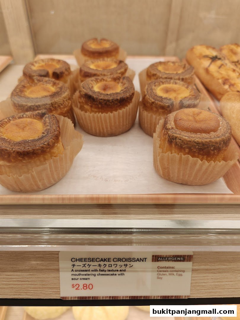 A close-up of freshly baked cheesecake croissants displayed in a bakery.