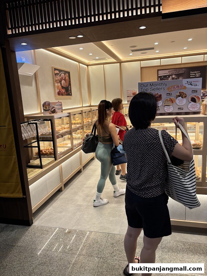 Customers browse baked goods at Gokoku Japanese Bakery, with a display of monthly top sellers.
