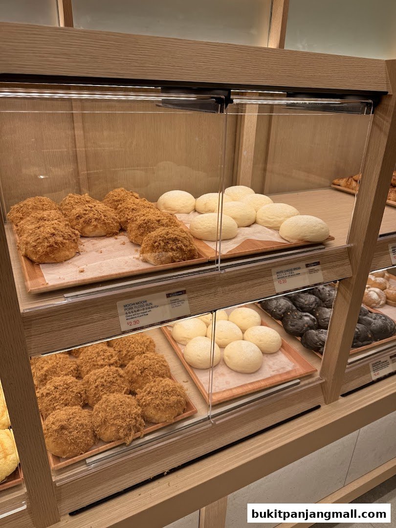 Display case filled with various freshly baked buns and bread at Gokoku Japanese Bakery.