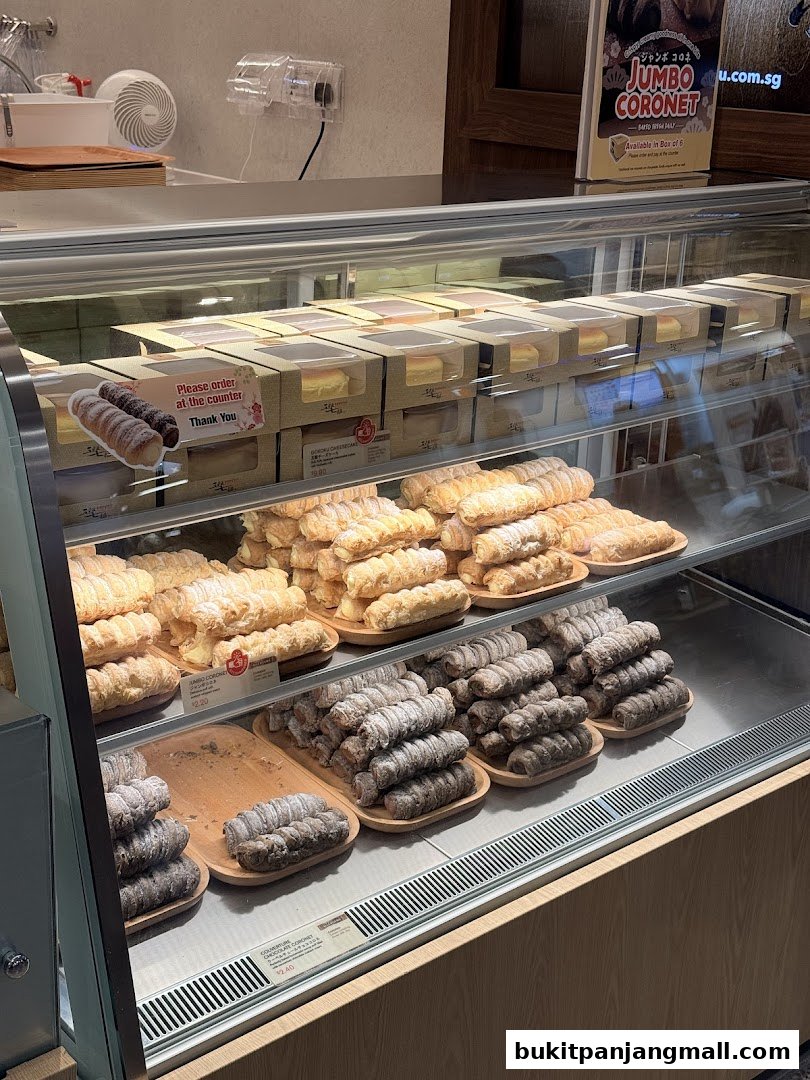 A display case filled with various types of pastries, including cream-filled rolls and cheesecakes.