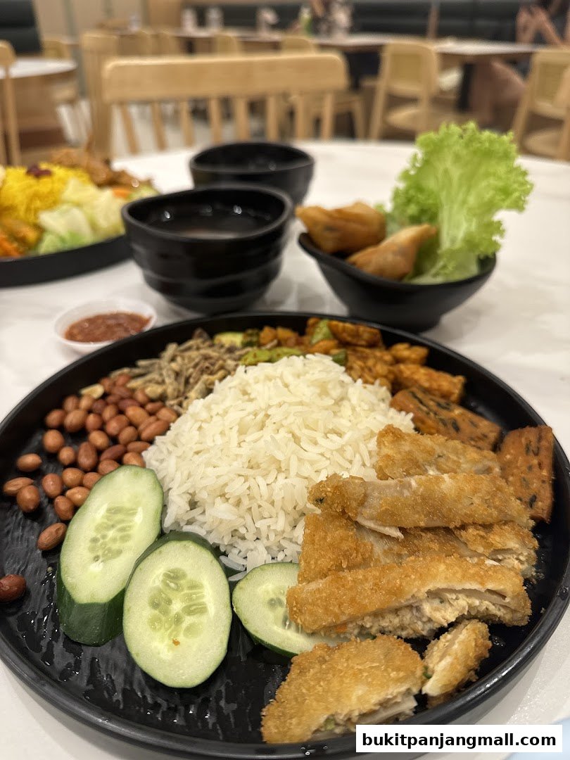 A close-up of a delicious meal featuring rice, fried chicken, cucumbers, peanuts, and sambal.