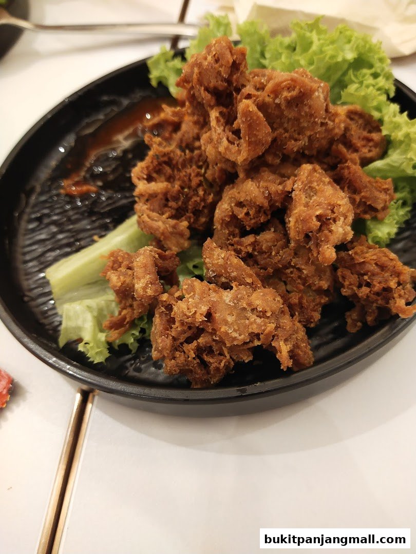 A plate of crispy fried food served with lettuce and a side of sauce.