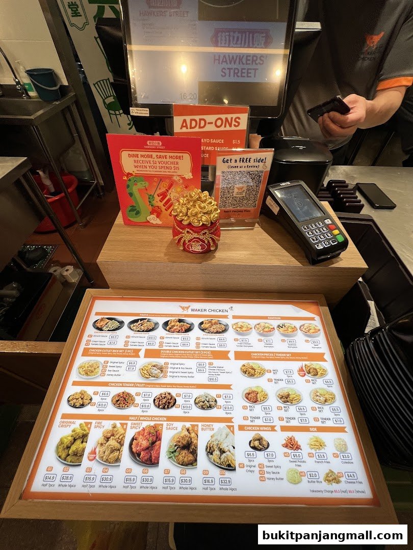 A brightly lit menu board displaying various chicken dishes and sides at Hawkers Street.