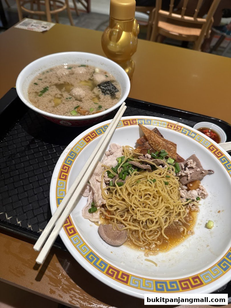 A bowl of noodles with meat and soup, served with chopsticks and a dipping sauce.