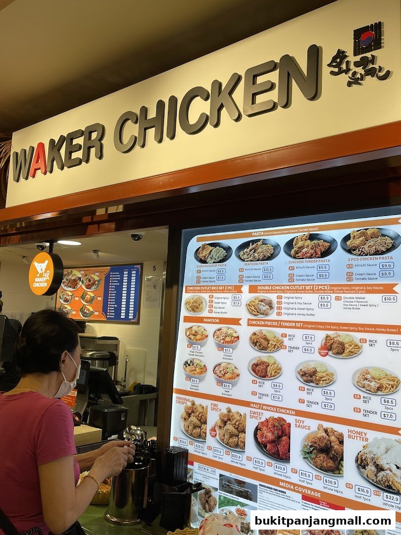 A customer orders from a brightly lit menu board at a Korean fried chicken restaurant.