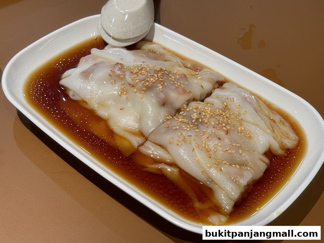 A close-up shot of delicious steamed rice noodle rolls with sesame seeds and sauce.