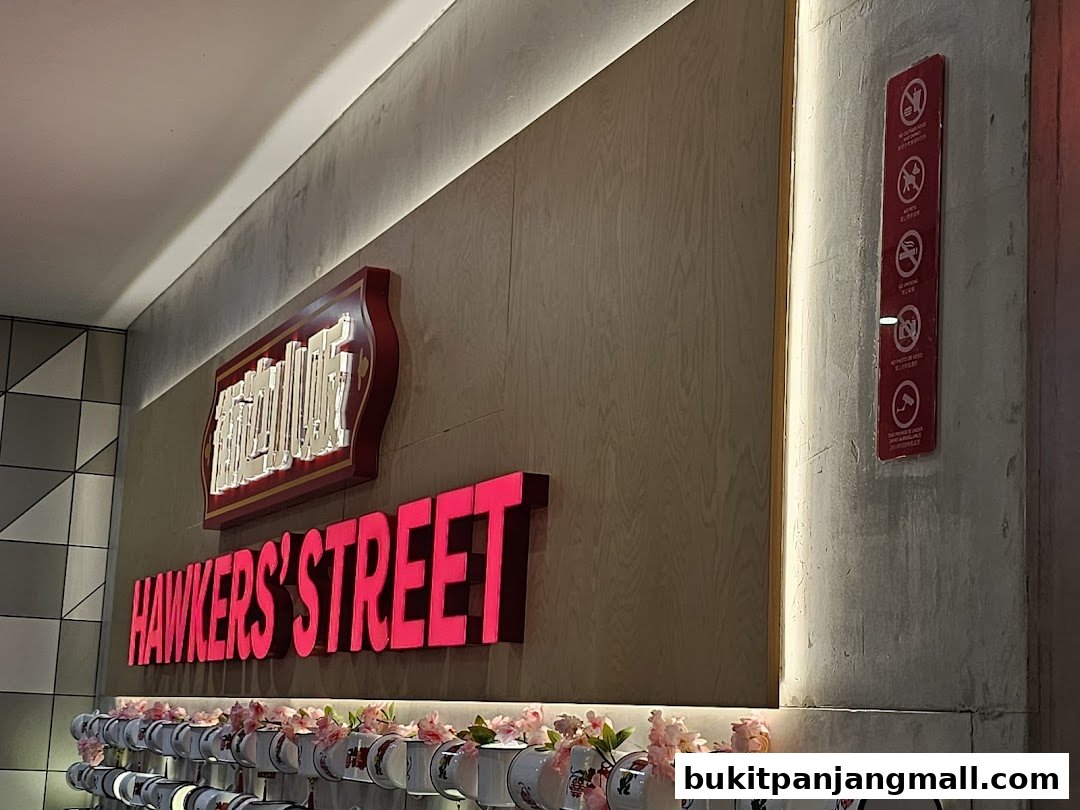 The illuminated sign for Hawkers' Street with decorative cups below.