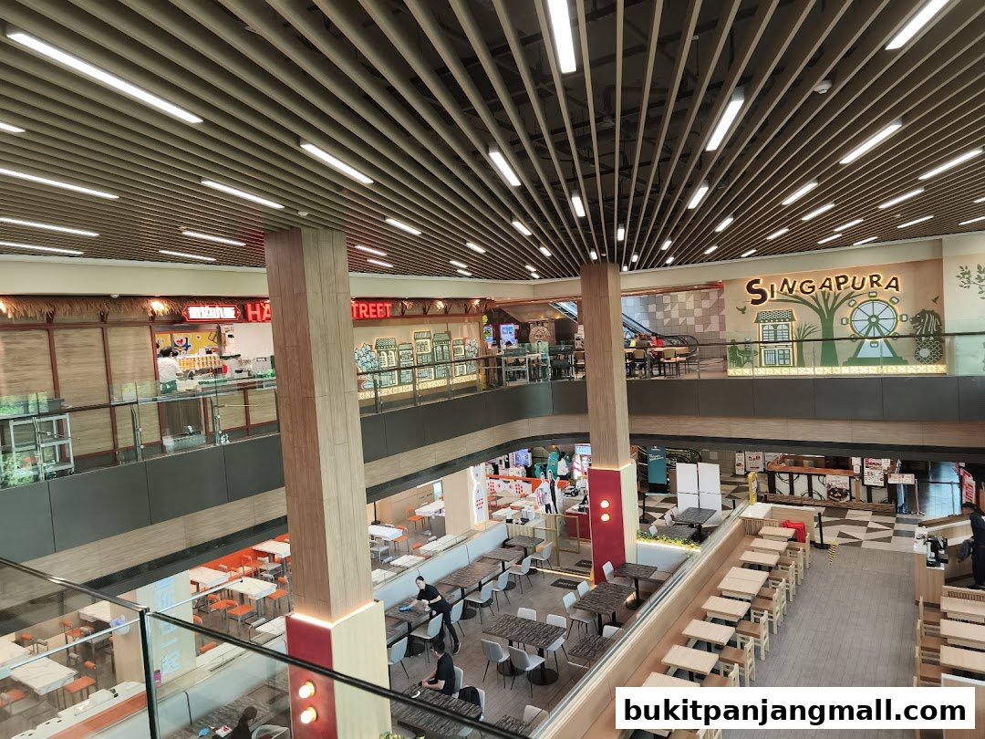 An interior view of a multi-level shopping mall with various food stalls and seating areas.