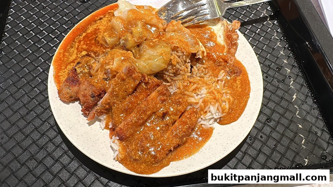 A plate of rice with fried chicken and curry sauce, served with a fork.