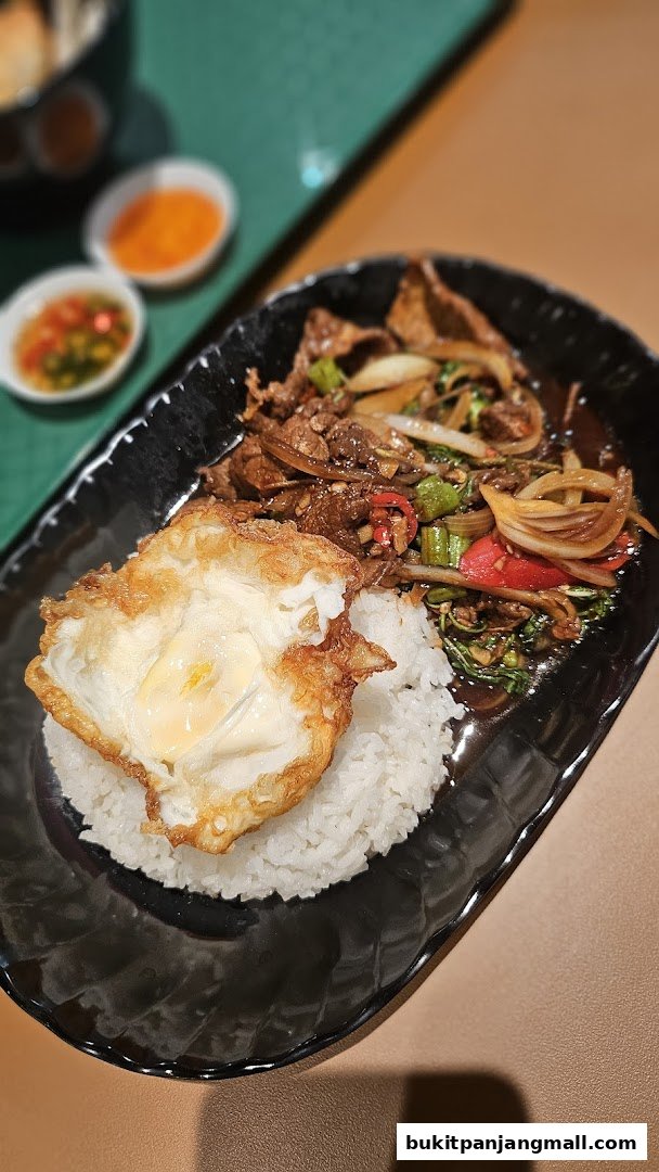 A plate of rice topped with stir-fried beef and vegetables, and a fried egg.