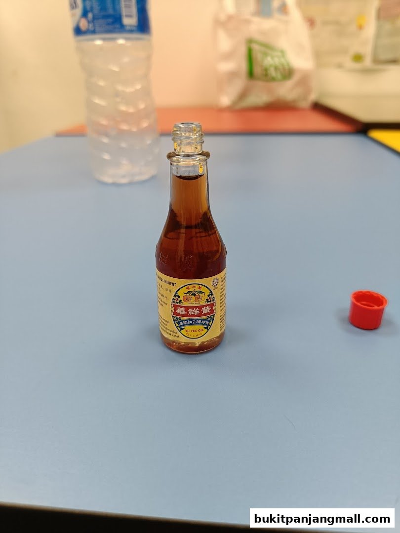 A small bottle of Yu Yee Oil from Hockhua Tonic with a red cap nearby.