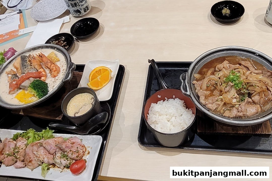 A table setting with two Japanese meals, featuring seafood, meat, rice, and side dishes.